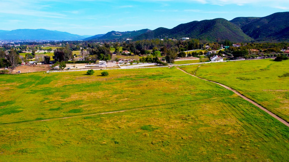 Aerial view of a green field with distant foothills